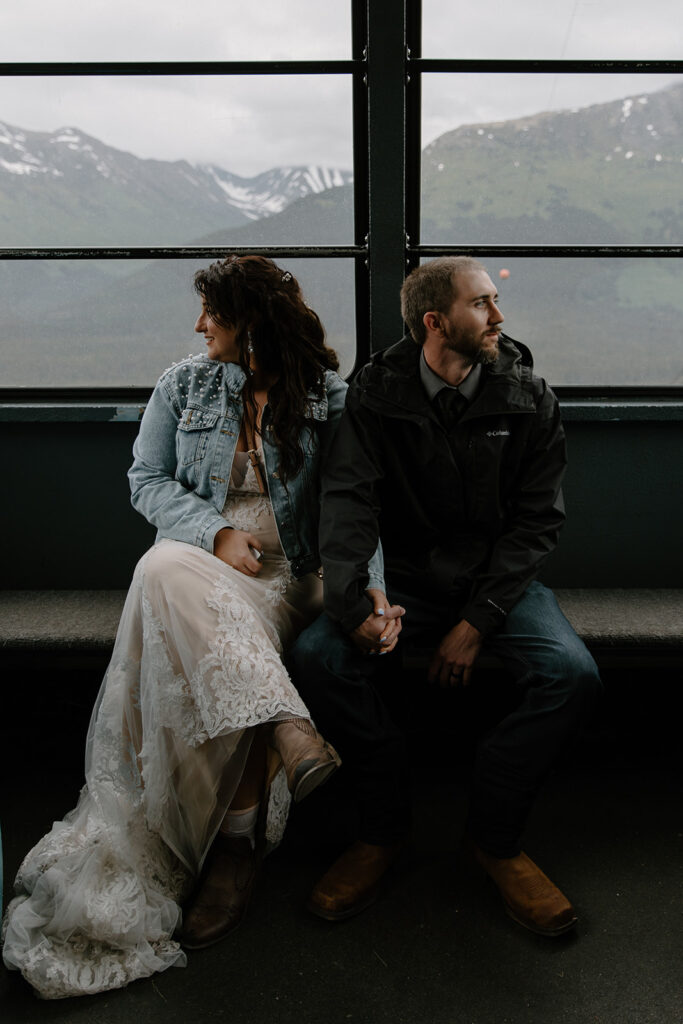 Bride and groom holding hands and gazing out the windows while riding the aerial tram at Alyeska Resort in Girdwood, Alaska.