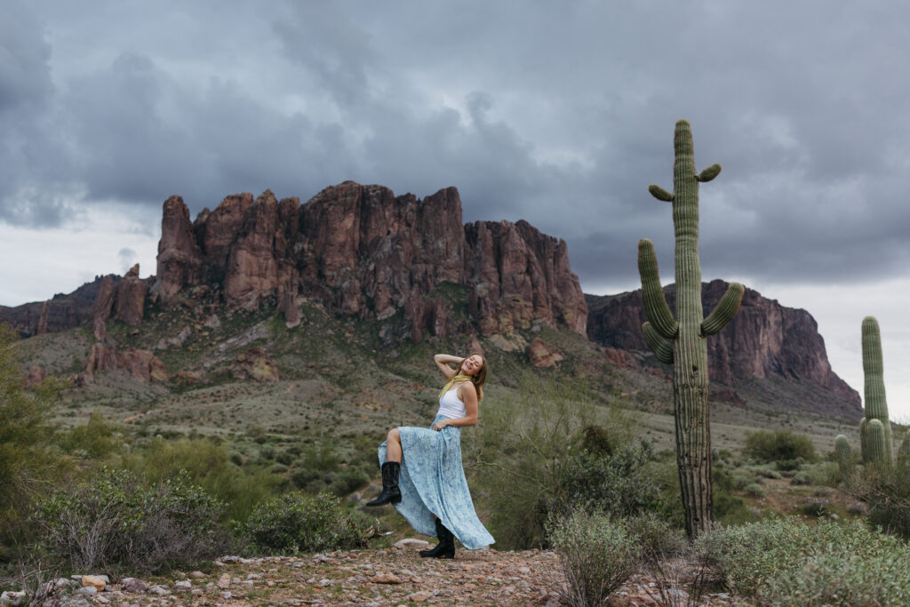 Photographer lifts up knee in excitement while standing in front of the Superstition Mountains