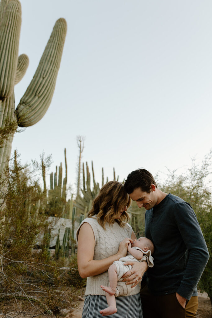 Mom, dad, and baby cradle baby. There are desert cacti surrounding them.