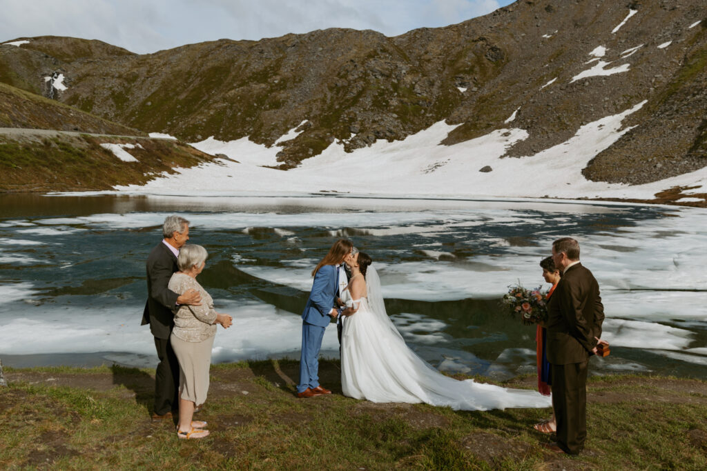 Bride and groom sharing their first kiss during their Hatcher Pass elopement ceremony at Summit Lake Alaska