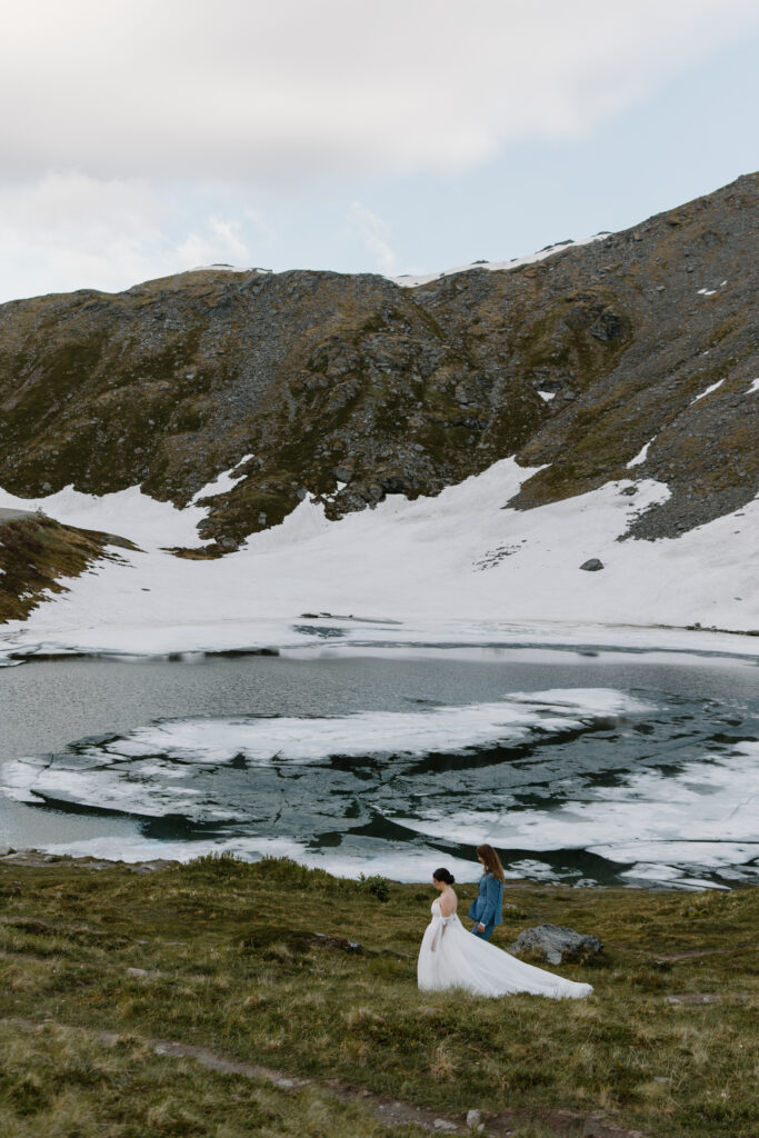 Bride and groom walking hand in hand along Summit Lake during their Hatcher Pass elopement in Alaska