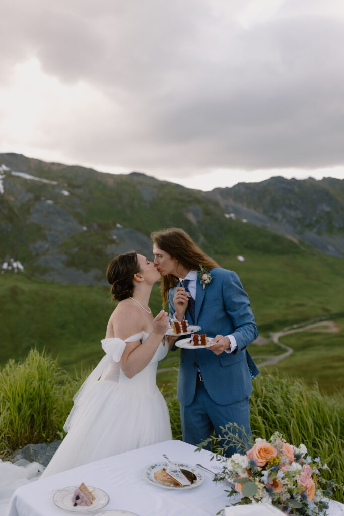 Bride and groom kissing after tasting their wedding cake during their Hatcher Pass elopement celebration