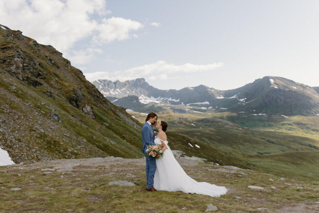 Bride and groom smiling at each other during their Hatcher Pass elopement with dramatic mountain peaks in the background near Summit Lake