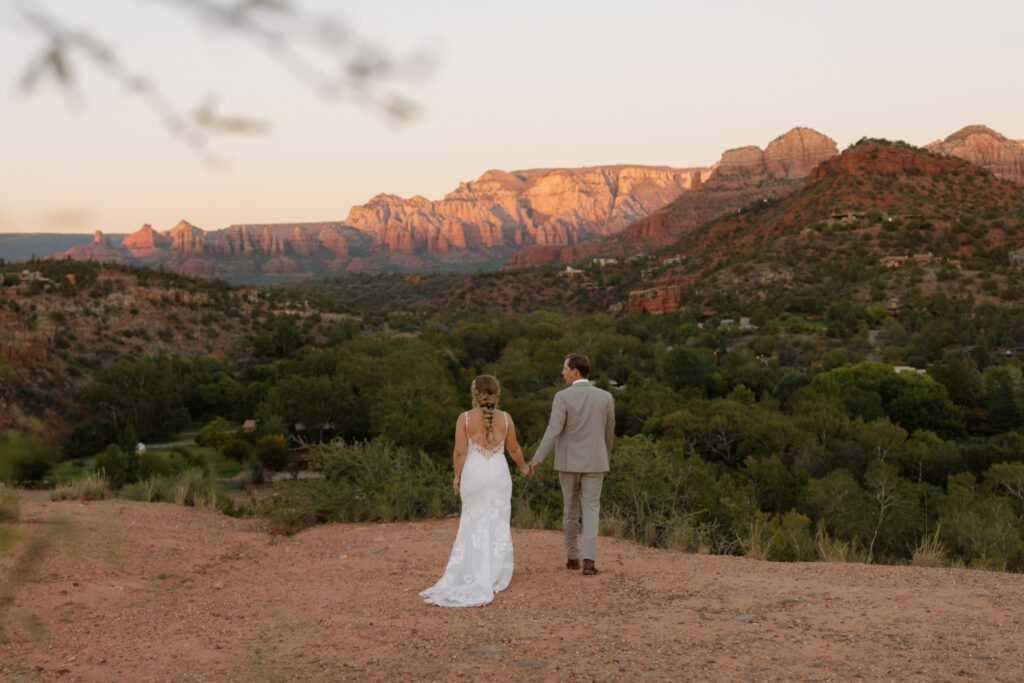 Bride and groom walking hand in hand toward the overlook during their Secret Slickrock elopement in Sedona Arizona