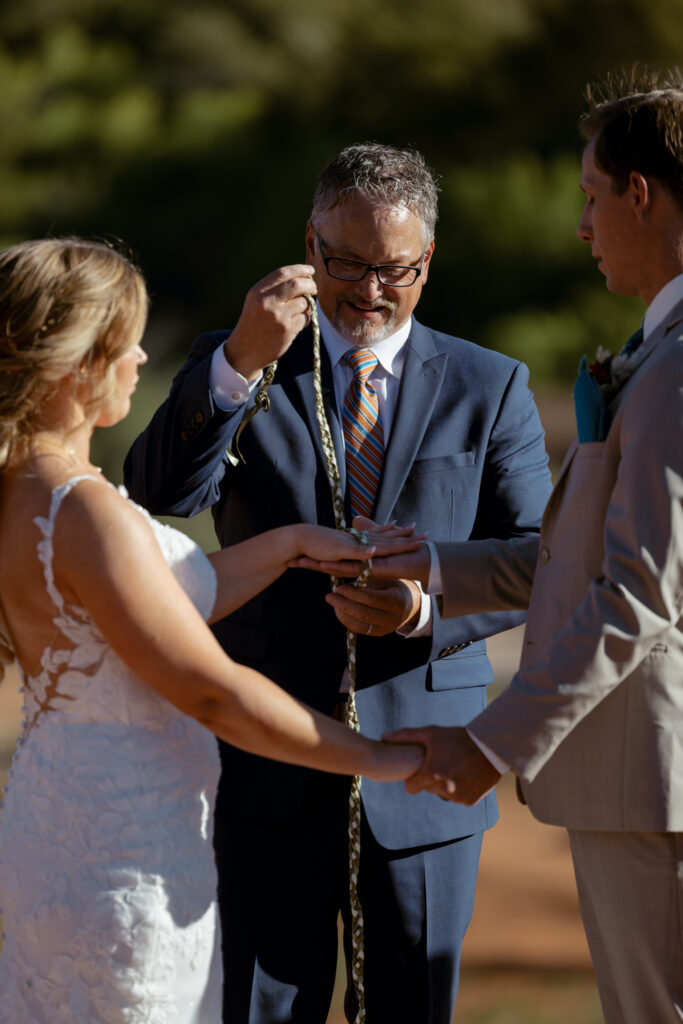 Bride and groom during hand fasting ritual at their Secret Slickrock elopement ceremony in Sedona Arizona