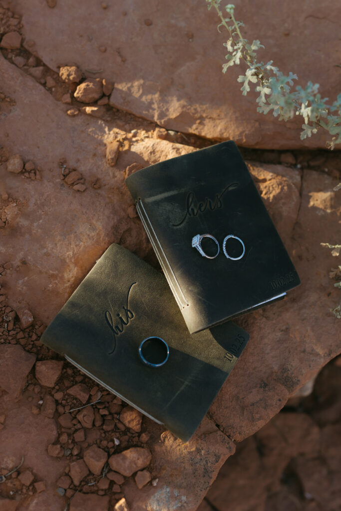 Wedding vow books and rings resting on the red rocks during a Sedona Arizona elopement at Secret Slickrock