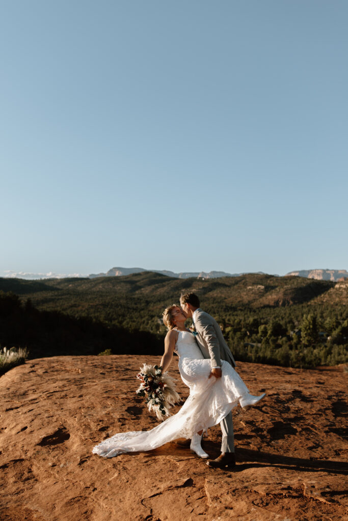 Groom dipping bride for a kiss during their Secret Slickrock elopement ceremony in Sedona Arizona
