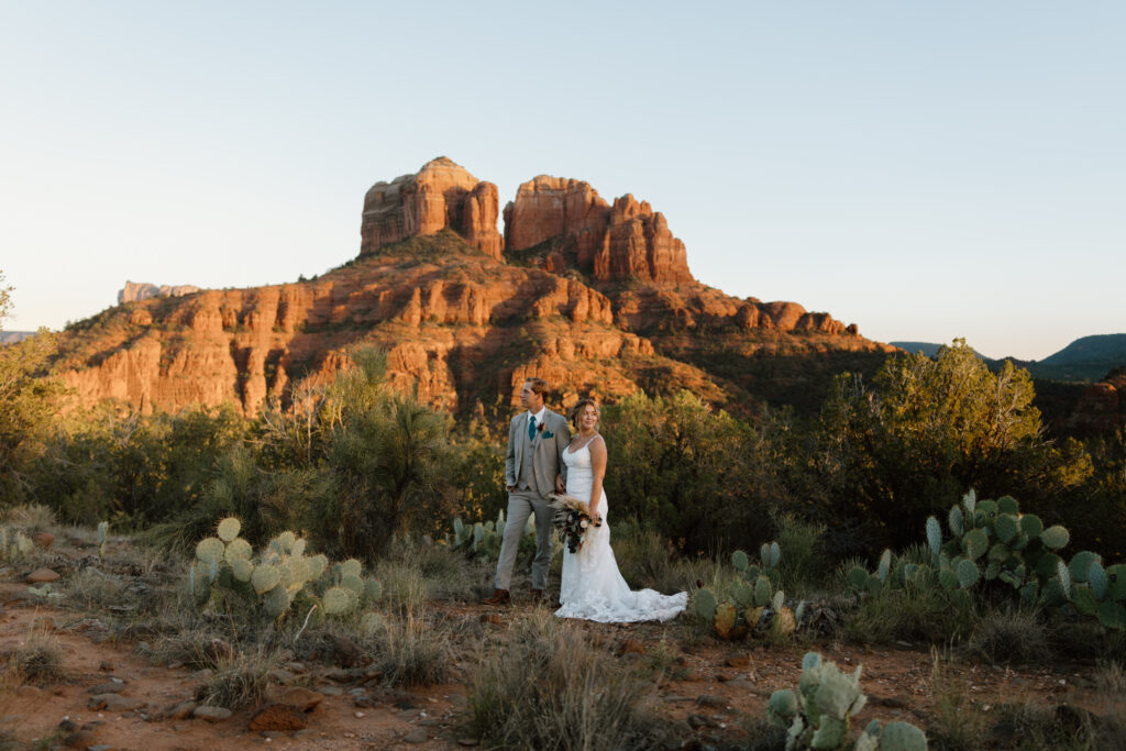 Bride and groom looking out toward Cathedral Rock surrounded by prickly pear cactus during their Sedona Arizona elopement at Secret Slickrock