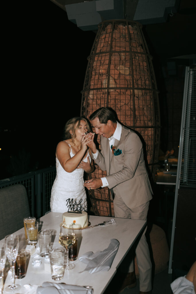 Bride and groom taking bites of wedding cake at their Sedona Arizona elopement celebration at Broome and Orchard