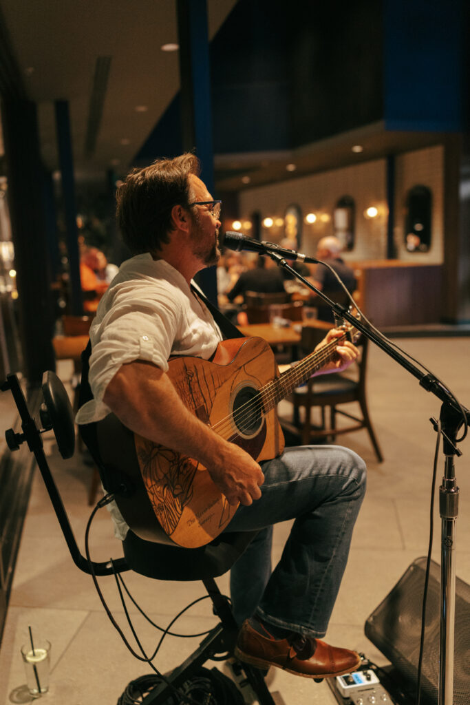 Live musician playing guitar and singing at Broome and Orchard restaurant in Sedona Arizona during an elopement celebration dinner