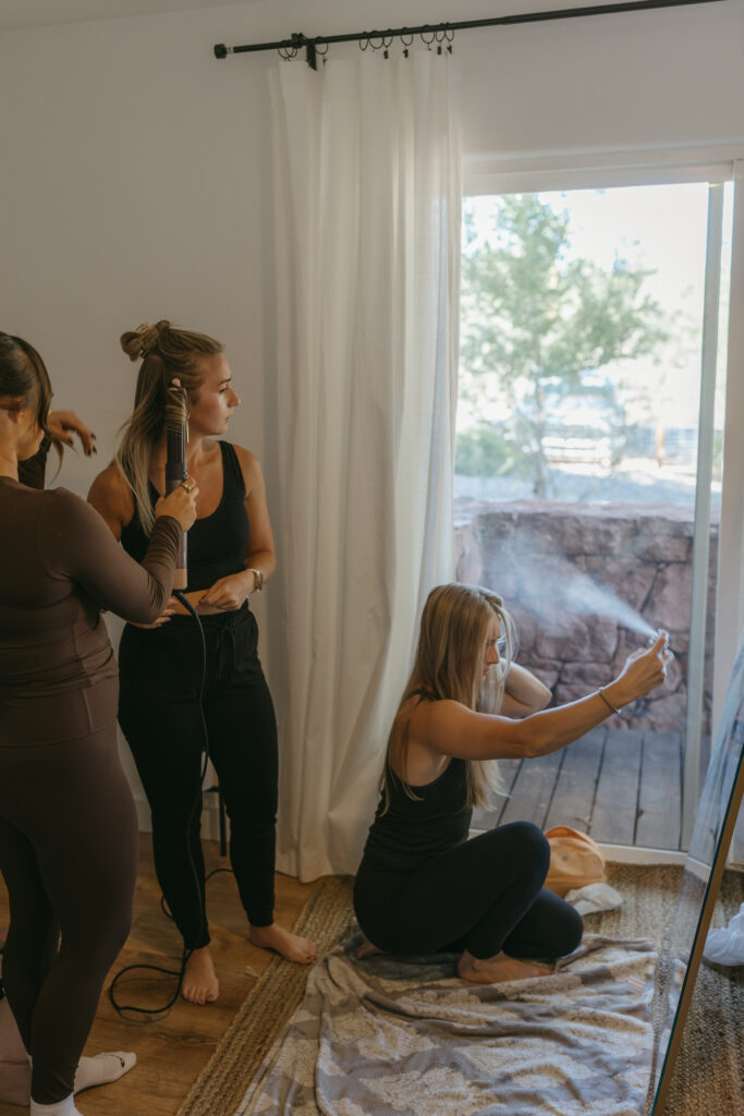 Bridesmaids getting ready together in the mirror at a Sedona Arizona Airbnb on elopement morning