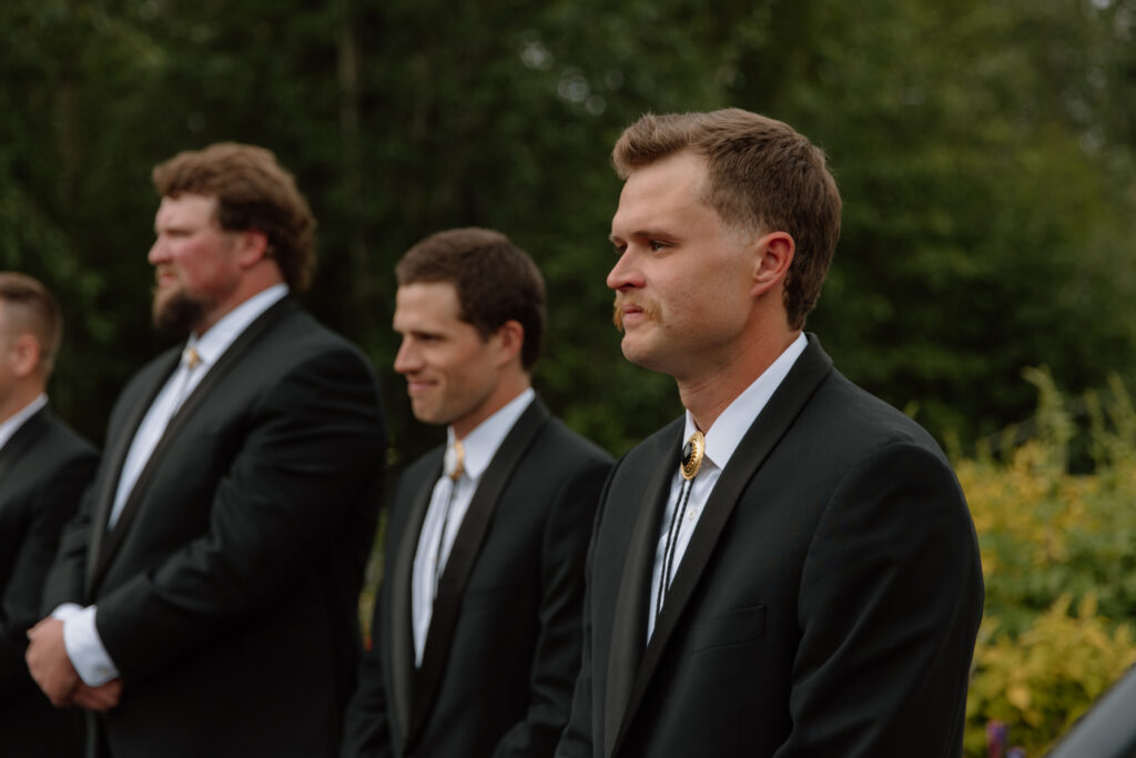 Groom with a tear in his eye watching the bride walk down the aisle.