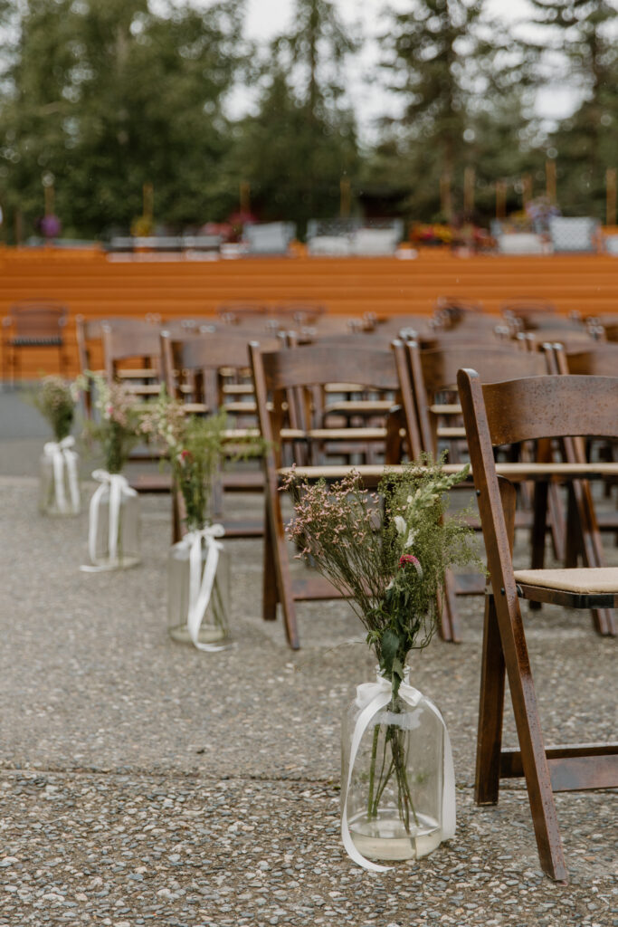 Ceremony chair details with glass vases and floral arrangements at an Alaska Native Heritage Center wedding in Anchorage Alaska