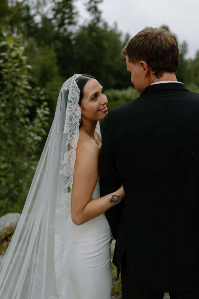 Bride resting her chin on groom's shoulder smiling up at him during wedding portraits