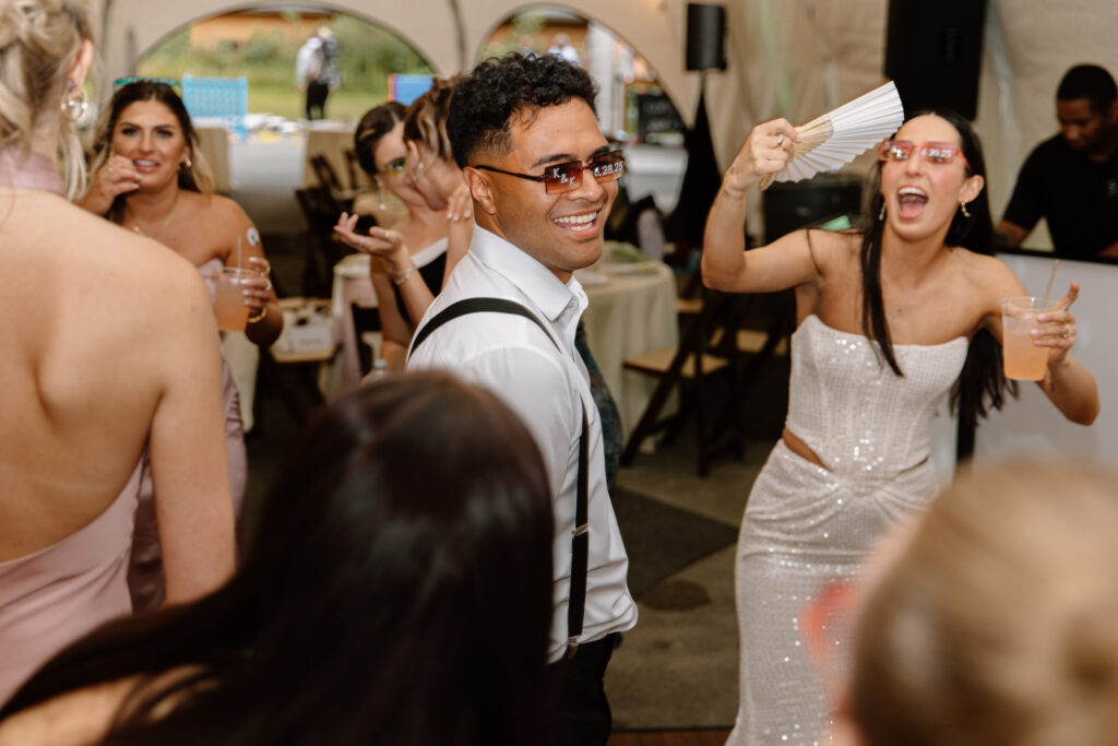 Guests smiling and dancing with the bride inside the reception tent at the Alaska Native Heritage Center wedding in Anchorage Alaska

