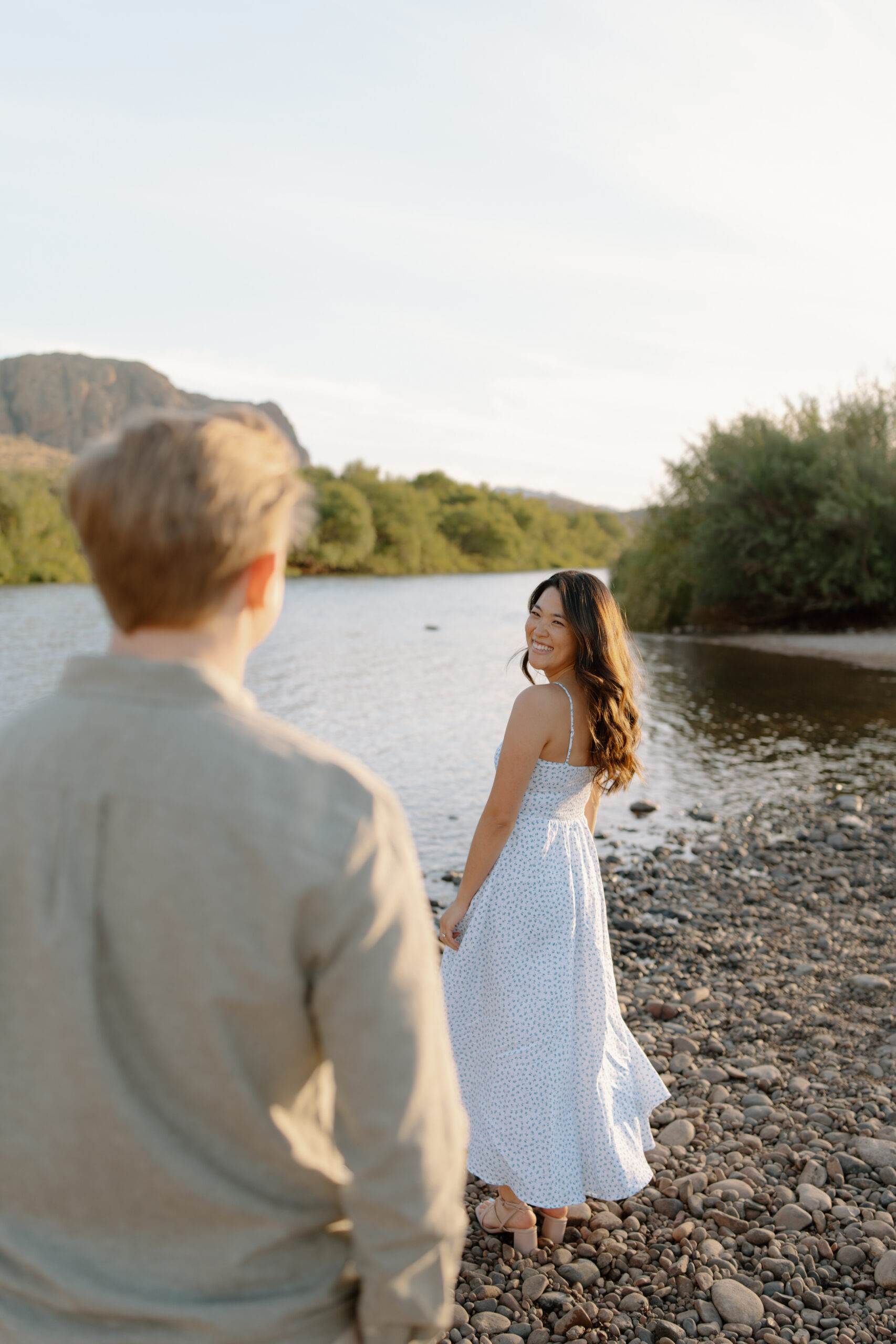Girl looking over shoulder at fiance as she twirls her dress in front of the Salt River Arizona